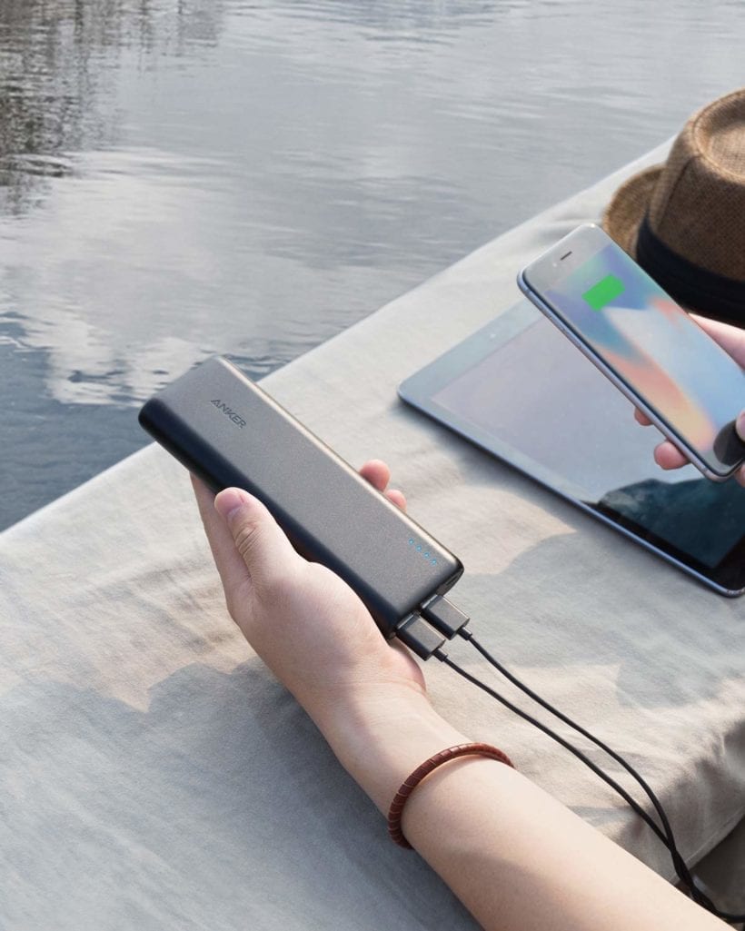 Image of Person holding Anker PowerCore 20100 plugged into phone and tablet while looking at lake