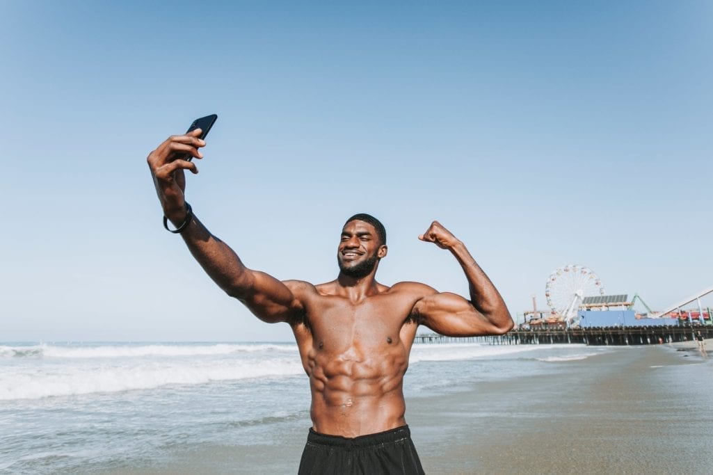 standing man on seashore taking selfie