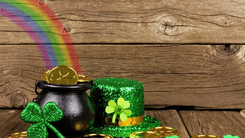 Image of Four Leaf Clovers, coins and top hat on Brown Wood Table