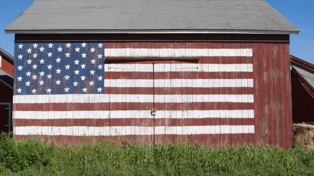 Image of a flag draped on exterior barn wall in field