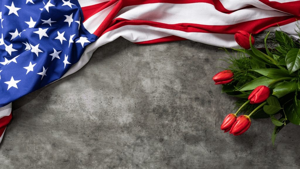 Image of Flag over grey cement with tulips nearby