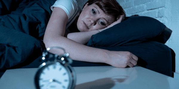 Image of woman trying to sleep while in a hotel
