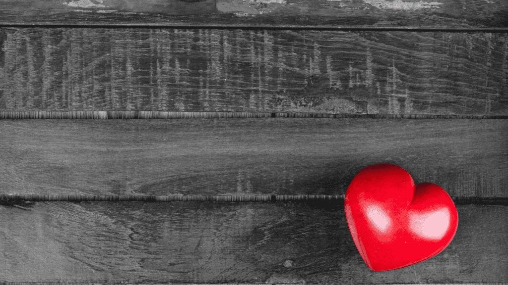 a red heart on a wooden surface